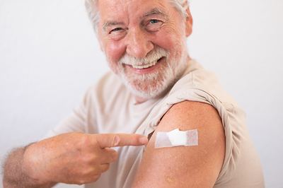 An older man pointing to the bandage on his arm after a vaccination